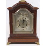 An early 20th century mahogany cased bracket clock, having an arched dial with silvered chapter