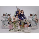 A Staffordshire flatback figure of a gentleman holding a set of bagpipes and a lady seated upon a