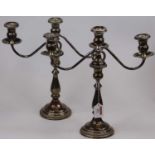 A pair of weighted American silver three-branch table candelabra, having scrolling arms upon a