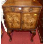 A small 1930s figured walnut double door bedside cupboard, having twin upper drawers on shell capped