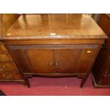 A 1930s oak freestanding hinge top gramophone, having twin cupboard doors with side winding arm,