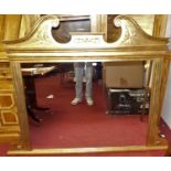A large contemporary gilt framed and floral decorated overmantel mirror, having scroll broken