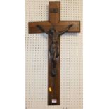A bronze model of Christ on the cross, mounted to a walnut backing