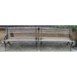 A pair of wrought iron ended black painted and teak slatted two-seater garden benches, each width