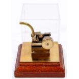 A miniature horizontal stationary steam engine, raised on wooden plinth with perspex display case,