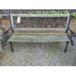 A black painted wrought metal and stained wood slatted two-seater garden bench (one seat slat