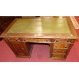 An early 20th century oak and gilt tooled green leather inset kneehole writing desk, having an