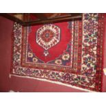 A Persian woollen red ground Bokhara rug, the central medallions within multiple trailing tramline