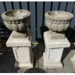 A pair of reconstituted stone footed cylindrical planters, raised on associated painted