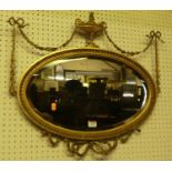 A circa 1900 French giltwood and gesso bevelled oval wall mirror, having urn and swag surmount and