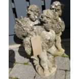 A set of three concrete cherub standing figures, each holding a carp, modelled as water features,