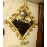 A contemporary giltwood lozenge shaped bevelled wall mirror, with floral C scroll outer