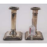 A pair of Edwardian filled silver table candlesticks, each having square sconce over a gun barrel