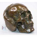 A modern bronzed model of a skull wearing headphones, height 16cm