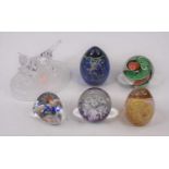 A collection of five coloured glass paperweights; together with a glass model of a cat and kitten,