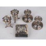 A pair of Edwardian silver peppers, each having a shaped rim over a cylindrical banded body, and