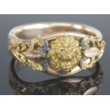 An Edwardian rolled gold hinged bangle, of good size, set with lion mask having faux ruby glass