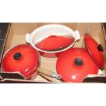 A collection of Le Creuset red enamel pans and cookware