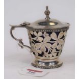 An Edwardian silver mustard of pierced cylindrical form, having a hinged lid surmounted by a finial,