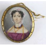 A Victorian pinchbeck framed mourning brooch depicting a bust portrait of a maiden wearing a lace