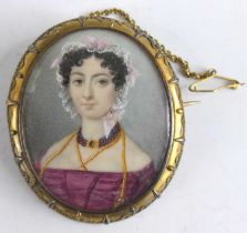 A Victorian pinchbeck framed mourning brooch depicting a bust portrait of a maiden wearing a lace