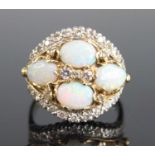 A yellow and white metal, opal and diamond bombe cluster ring, featuring a centre quatrefoil of oval