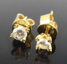 A pair of yellow metal diamond single stone stud earrings, each with a round brilliant cut diamond