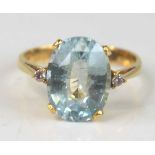 A yellow metal aquamarine and diamond dress ring, featuring an oval faceted aquamarine with a