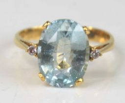 A yellow metal aquamarine and diamond dress ring, featuring an oval faceted aquamarine with a