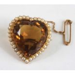 A yellow metal heart shaped citrine brooch, the citrine within a border of thirty-four 2.2mm seed
