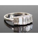 A white metal diamond half hoop ring, featuring five graduated emerald cut diamonds in bezel