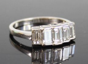 A white metal diamond half hoop ring, featuring five graduated emerald cut diamonds in bezel