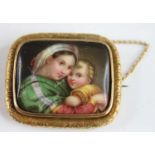 A yellow metal painted porcelain miniature brooch depicting a mother and child, within an engraved