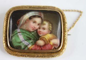 A yellow metal painted porcelain miniature brooch depicting a mother and child, within an engraved