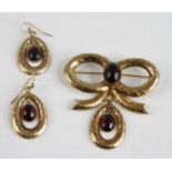 A 9ct yellow gold garnet brooch and earrings set, the brooch in the form of a bow with an