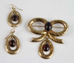 A 9ct yellow gold garnet brooch and earrings set, the brooch in the form of a bow with an