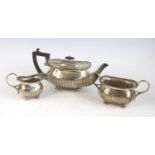 An Edwardian silver three-piece tea service, comprising teapot, twin handled sugar and cream, each