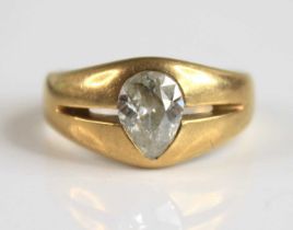 A yellow metal diamond solitaire ring, featuring an old pear cut diamond flush set within a boat