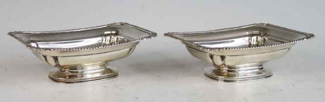 A pair of silver pedestal butter dishes, each having gadrooned rim with shell capped corners,