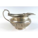 A late Victorian silver helmet shaped cream jug, the half-reeded body with a beaded and floral