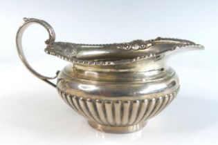 A late Victorian silver helmet shaped cream jug, the half-reeded body with a beaded and floral