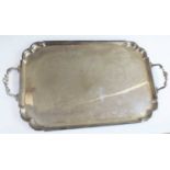 A large and heavy Elizabeth II silver twin handled serving tray, of shaped rectangular form with