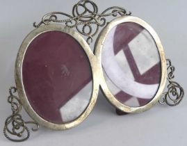 A George V silver double photograph frame, the co-joined circular frames having applied scrolling