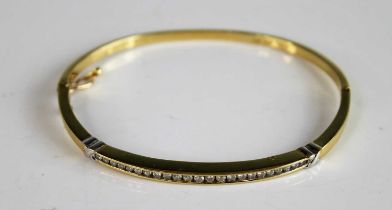 A yellow and white metal diamond hinged hollow oval bangle, featuring 23 round brilliant cut