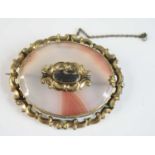 A yellow metal Victorian agate memorial brooch, featuring a banded agate within a scrollwork