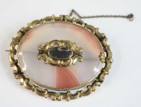 A yellow metal Victorian agate memorial brooch, featuring a banded agate within a scrollwork