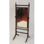 A Regency mahogany cheval mirror, the rectangular plate within a ring turned skeleton surround, on