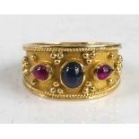 A yellow metal Etruscan style dress ring, having a centre oval synthetic sapphire and two