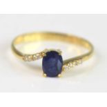 A yellow metal sapphire and diamond crossover style dress ring, having a centre oval sapphire and