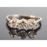 A white metal diamond three-stone ring, featuring three graduated round brilliant cut diamonds in